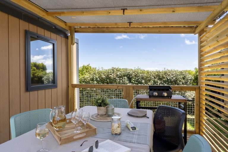 Zonnig terras met tafel en barbecue.